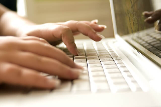 Mão de uma mulher digitando no teclado do computador